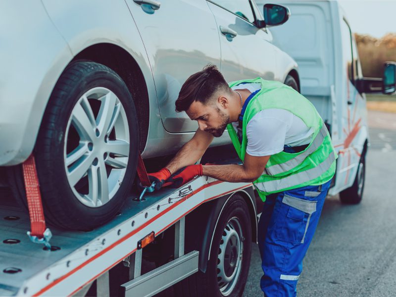 Mand sætter bil på transporter