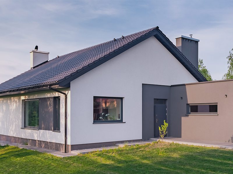 Hvidt hus med sort tag og grønt græs