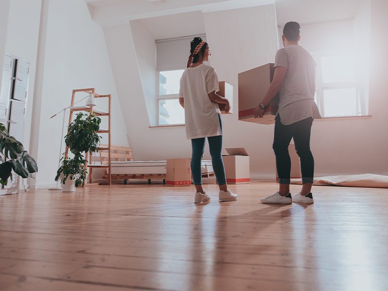 Unge flytter med papkasser i tom lejlighed