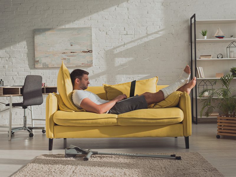 Mand i gul sofa med brækket ben