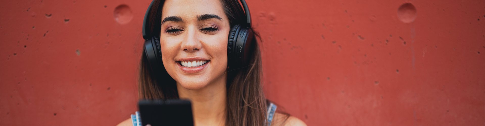 Ung pige med hørebøffer og telefon