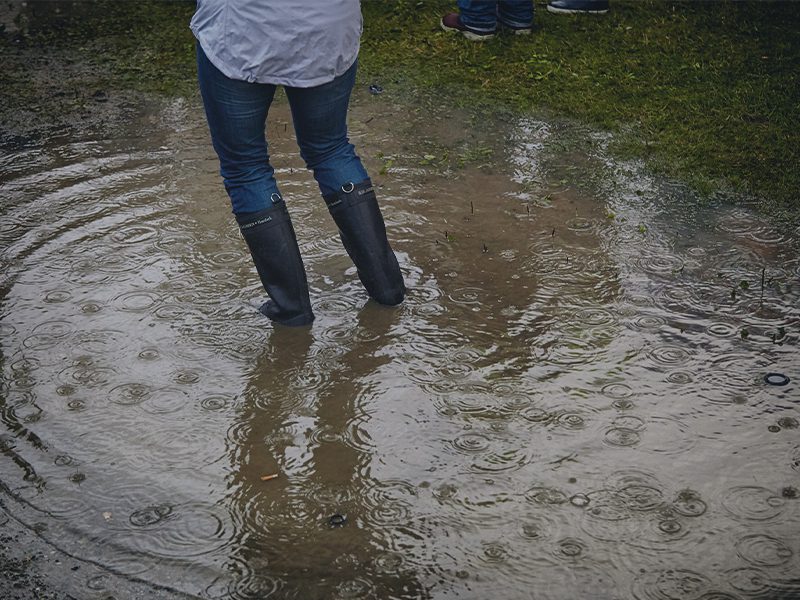 Kvinde i en stor vandpynt under regnvejr