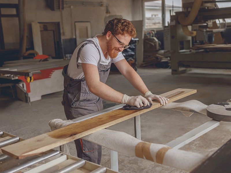 Mand arbejder med tømmer i værksted